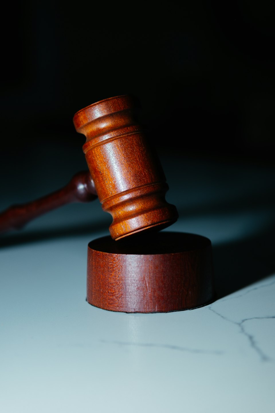 Wooden gavel resting on its sound block on a marble surface.